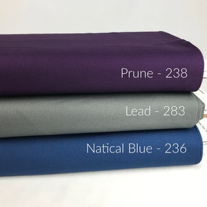 Puede incluir: Tres muestras de tela apiladas una encima de la otra. La muestra superior es de color morado oscuro y está etiquetada como "Prune - 238". La muestra del medio es de color gris claro y está etiquetada como "Lead - 283". La muestra inferior es de color azul oscuro y está etiquetada como "Nattical Blue - 236".