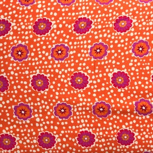 May include: Orange fabric with a white polka dot pattern and a repeating floral design in shades of pink, orange, and yellow.