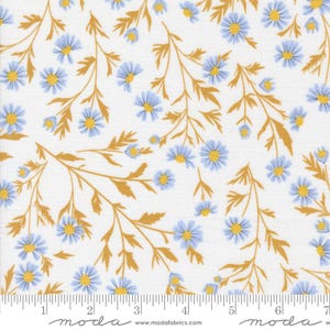 May include: White fabric with a repeating pattern of blue daisies with yellow centers and golden-brown stems and leaves. The fabric has a ruler along the bottom edge with the word "moda" printed on it.