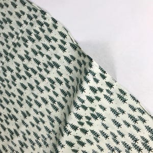 May include: White fabric with a repeating pattern of green pine trees and small white dots.