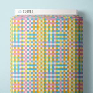May include: A bolt of fabric featuring a repeating woven plaid pattern in bright shades of pink, yellow, orange, and light blue. The top edge of the fabric roll displays a white label with a cloud icon and the text CLOUD9 printed in black.