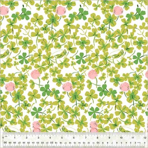 以下が含まれることがあります： 白地に緑のクローバー、ピンクの花、小さな緑のバッタが繰り返されるデザインの生地パターン。クローバーは3枚または4枚の葉を持っています。パターンはセンチメートルで測定されます。