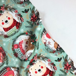 May include: A green fabric with a repeating pattern of white polar bears wearing red scarves, brown deer wearing red hats, and green wreaths with red berries and poinsettia flowers.