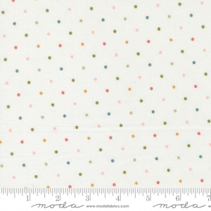 May include: Cream-coloured fabric featuring a repeating pattern of multi-coloured polka dots. The dots are in shades of pink, green, blue, and orange. A ruler is at the bottom of the fabric, with the word "moda" printed on it.