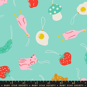 May include: A light teal fabric featuring a repeating pattern of hanging ornaments shaped like pink geese, fried eggs, strawberries, mushrooms, and pickles. A black ruler at the bottom shows measurements in inches, labelled Ruby Star Society.