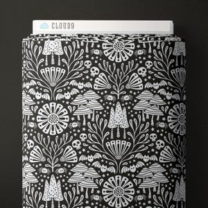 May include: A roll of black fabric with a white, repeating pattern of mushrooms, flowers, bats, spiders, and skulls. The fabric is labeled "CLOUD9" at the top. The design is a whimsical, gothic-inspired illustration.