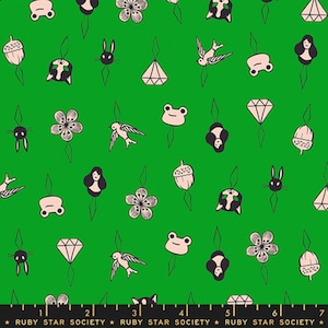 May include: A vibrant green fabric featuring a repeating pattern of light pink and black line-art illustrations of frogs, flowers, birds, rabbits, acorns, diamonds, and faces, with a black ruler at the bottom marked up to 7 inches.