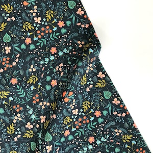 Peut inclure: Tissu bleu marine fonc&eacute; avec un motif floral color&eacute;. Le motif pr&eacute;sente de petites fleurs p&ecirc;che, bleues et blanches, ainsi que des feuilles et des tiges vertes et jaunes. Le tissu est pli&eacute;, montrant l'impression d&eacute;taill&eacute;e.