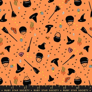 May include: An orange fabric featuring a repeating pattern of black witch hats, black cauldrons with orange contents, black broomsticks, small white skulls, blue mushrooms, orange snails, and yellow stars. The bottom edge shows a black ruler.