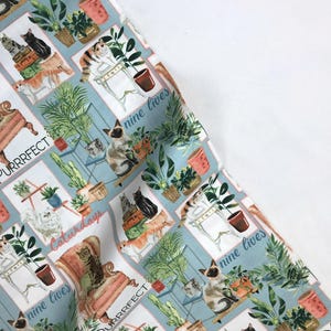 Może przedstawiać: Niebieska i biała tkanina z powtarzającym się wzorem kotów, roślin i tekstem "Purrfect" i "Nine Lives".