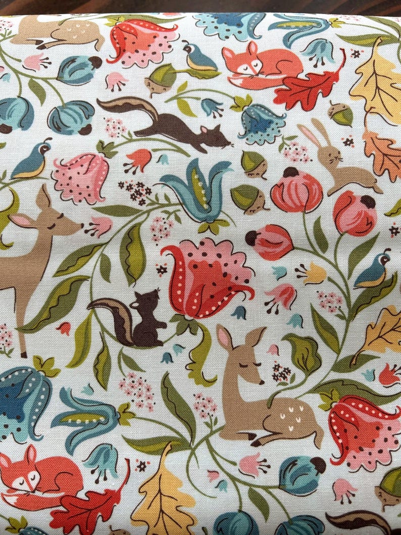 K&ouml;nnte beinhalten: Wei&szlig;er Stoff mit einem skurrilen Waldmuster. Das Design zeigt Hirsche, F&uuml;chse, Eichh&ouml;rnchen, Kaninchen, V&ouml;gel und Blumen in Rot-, Orange-, Blau- und Gr&uuml;nt&ouml;nen. Der Stoff hat ein sich wiederholendes Muster aus Waldtieren und floralen Elementen.
