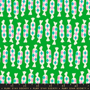 Puede incluir: Una tela verde con un patrón repetido de caramelos blancos con formas de diamantes rosas y turquesa.