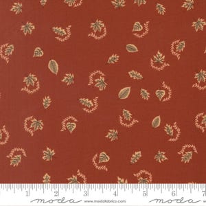 Può includere: Un tessuto color ruggine con un motivo ripetuto di piccole foglie chiare e rametti curvi. Sul bordo inferiore è visibile un righello bianco con misure in cm, insieme al testo moda e www.modafabrics.com.