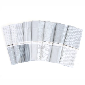 May include: A set of eight folded fabric pieces arranged in a fan shape, each featuring different gray and white geometric patterns including crosses, dots, and stripes. A white paper band labeled Mod Textures wraps around each piece of fabric.
