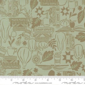 Op de afbeelding: Een licht saliegroene stof met een herhalend bruin lijnpatroon van stapels boeken, mokken, pompoenen, bladeren en stervormen. Een witte liniaal onderaan toont afmetingen in cm met de tekst moda fabrics.