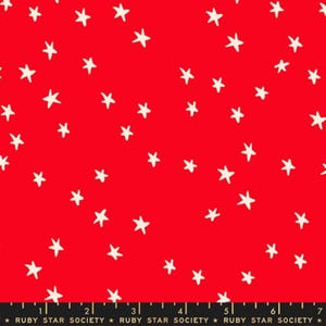 May include: Red fabric featuring a pattern of white stars. The stars are randomly arranged. A black ruler with the text "RUBY STAR SOCIETY" is at the bottom of the fabric.