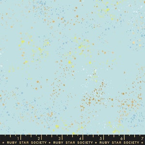 Op de afbeelding: Een lichtblauwe stof met een gespikkeld patroon van gouden, witte en lichtblauwe stippen.