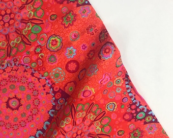 May include: Red fabric with a colorful, abstract pattern of circles, swirls, and flowers. The fabric has a bright, vibrant color scheme.