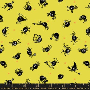 Può includere: Un tessuto giallo con un motivo ripetuto di ragni neri in stile cartoon impegnati in varie attività, tra cui leggere, indossare cappelli e tenere oggetti. Il bordo inferiore mostra un righello nero con il testo Ruby Star Society.