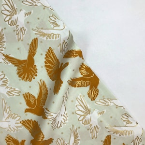 May include: A light green fabric with a repeating pattern of white and gold doves and gold birds. The background is a light green color with a subtle sparkle.