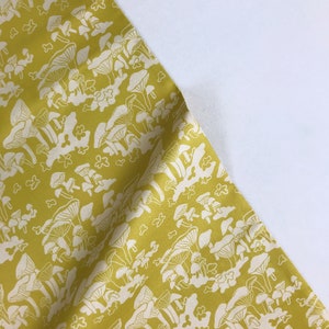 May include: Yellow fabric with a white mushroom print. The mushrooms are clustered together and have a whimsical design.
