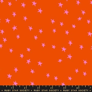 Op de afbeelding: Fel oranje stof met een verspreid patroon van roze sterren. De stof heeft een speels, grillig ontwerp, geschikt voor diverse knutselprojecten of kleding. De tekst "RUBY STAR SOCIETY" staat onderaan.