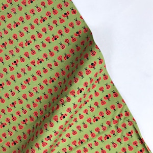Peut inclure: Tissu vert avec un motif répété de coccinelles rouges avec des points noirs.