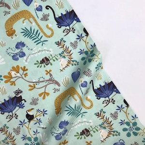 Puede incluir: Una tela verde menta con un patrón repetido de animales de la selva, incluyendo leopardos, tucanes y pájaros. La tela está cubierta de una variedad de follaje verde, azul y marrón.