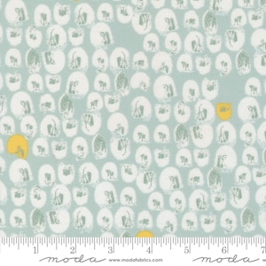 May include: Light blue fabric with a repeating pattern of white and gray brushstroke-style shapes. Scattered yellow shapes add pops of color. The fabric is marked with a ruler and the word "moda".