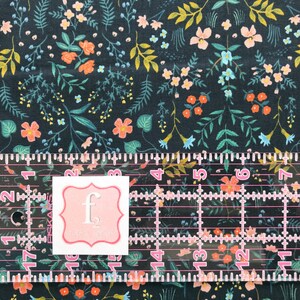 Peut inclure: Tissu bleu marine fonc&eacute; avec un motif floral compos&eacute; de fleurs et de feuillages orange, roses, jaunes et turquoise. Une r&egrave;gle transparente avec des marquages roses et une &eacute;tiquette blanche avec un bord rose et la lettre "f".