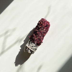 Könnte beinhalten: Weißer Salbei-Reinigungsstab, umwickelt mit getrockneten Rosenblüten. Der Reinigungsstab ist mit einem weißen Band gebunden.