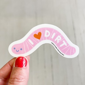May include: Pink worm sticker with a smiling face and a heart that says "I love dirt".