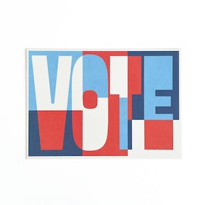 May include: A rectangular card featuring the word "VOTE" in large, overlapping letters. The letters are in white, red, and blue, with a geometric design. The background is white.
