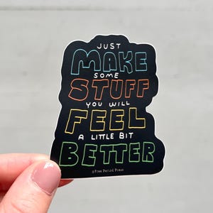 May include: A black die-cut sticker featuring the colorful text JUST MAKE SOME STUFF YOU WILL FEEL A LITTLE BIT BETTER. The lettering uses a hand-drawn style with outlines in blue, orange, yellow, and green. The text Free Period Press is at the bottom.