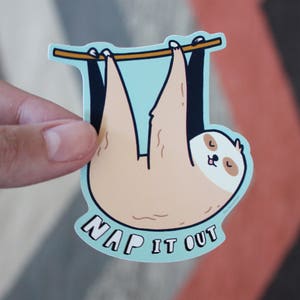 May include: A sticker featuring a cartoon sloth hanging from a branch with the text "Nap It Out". The sloth is brown and has a light blue background.