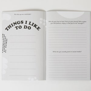 K&ouml;nnte beinhalten: Ein grau-wei&szlig;es Journal mit dem Text "Things I Like To Do" auf dem Cover. Das Journal hat linierte Seiten zum Schreiben. Der Text "Pin this up as a reminder!" steht oben auf der Seite. Das Journal hat zwei Seiten offen, mit Fragen zu sozialen Medien und wer Sie gerne am Telefon h&ouml;ren.