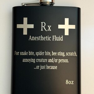 May include: A black 8oz flask with a silver top and engraved text that reads "Rx Anesthetic Fluid" and "For snake bite, spider bite, bee sting, scratch, annoying creature and/or person...or just because".