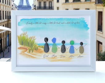 Pode incluir: Uma peça de arte de parede emoldurada com uma cena de praia em aquarela com cinco figuras feitas de vidro do mar e seixos de mãos dadas. O texto diz: Family a little bit crazy, a little bit loud, and a whole lot of love. Os nomes Dad, Mom, Peter, Alice e Annie estão impressos abaixo de cada figura.