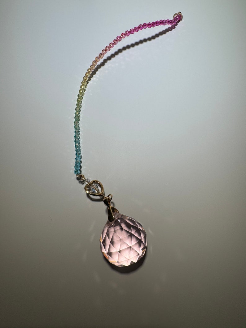 May include: A rainbow colored beaded chain with a clear pink crystal ball pendant.