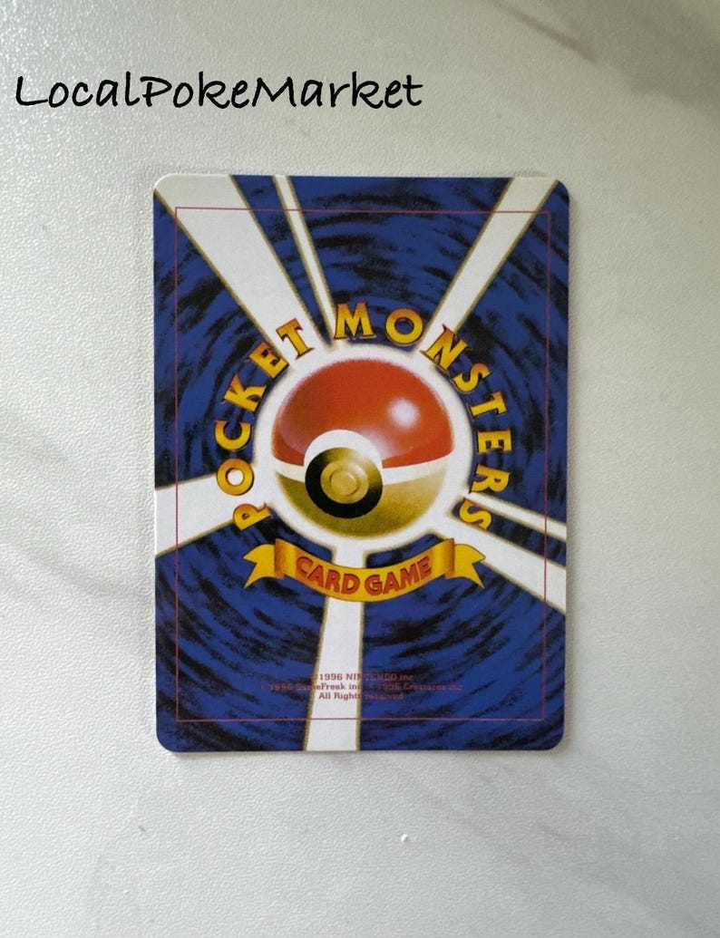 Puede incluir: Parte posterior de una carta de comercio de Pokemon con un fondo azul y un logotipo de Pokeball amarillo y rojo. El texto "Pocket Monsters Card Game" est&aacute; impreso en una pancarta amarilla.