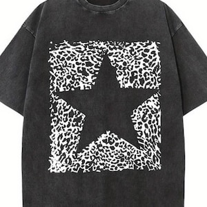 May include: Black t-shirt featuring a large black star design overlaid on a white leopard print pattern. The t-shirt has a crew neck and short sleeves. The fabric has a faded, vintage look.