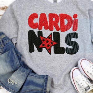 May include: A heather gray sweatshirt with the word "CARDINALS" in red and black, with a star graphic. The sweatshirt is paired with blue jeans and white sneakers.