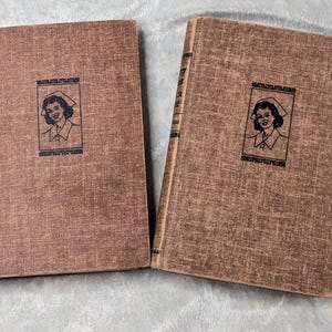 May include: Two vintage brown hardcover books. Each book has a portrait of a woman in a nurse's cap on the cover, framed by text. The books are lying side by side.