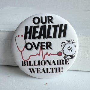 May include: A white button badge with the words "OUR HEALTH OVER BILLIONAIRE WEALTH!" in black. A red stethoscope and heartbeat line are on the left. A cartoon man carries a money bag on the right.