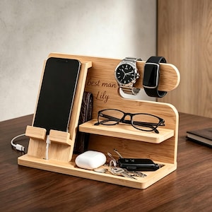 Pu&ograve; includere: Una docking station in bamb&ugrave; con supporto per telefono e cavo di ricarica, un ripiano per occhiali e un gancio per orologi. Il legno &egrave; inciso con il testo "best man" e "Lily". La base ospita una custodia bianca per auricolari e un mazzo di chiavi.