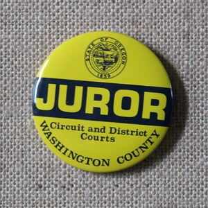 May include: Yellow round button with black text that reads "JUROR Circuit and District Courts WASHINGTON COUNTY". The button also features a black and white seal with the text "STATE OF OREGON 1859".