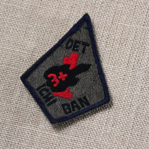 May include: A green and black embroidered patch with a red cross and the text "DET 3+ ICHIBAN".