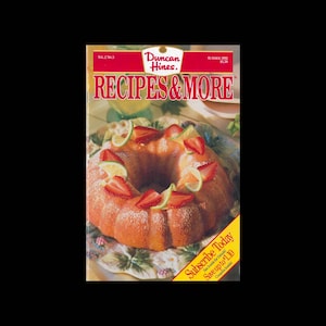 Puede incluir: Una portada de revista que presenta una revista Duncan Hines Recetas y Más con una foto de un pastel de cítricos cubierto con fresas y rodajas de lima. La portada de la revista es roja y blanca con el texto "Duncan Hines Recetas y Más" en letras grandes y negritas. El texto "Suscríbete hoy" está en un cuadro amarillo en la esquina inferior derecha de la portada.