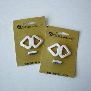 May include: Two packages of white plastic buckle straps with the text "Streamline®" and "C502 3/4" 81 10" printed on the packaging.