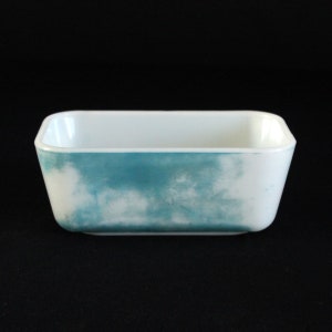 Puede incluir: Un molde para hornear rectangular blanco con un diseño de nubes azules y blancas.